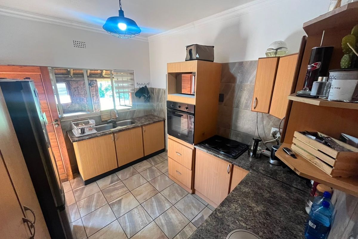 A functional kitchen featuring wood-finish cabinetry, granite-look laminate countertops, built-in oven and hob, tiled backsplash, and tiled flooring.