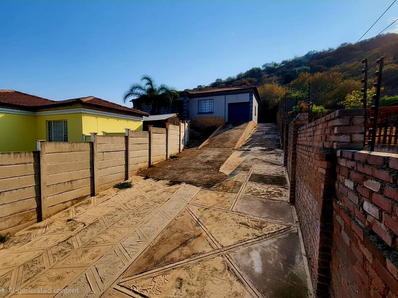 Front exterior view showing a concrete driveway leading to a garage, enclosed by precast and brick boundary walls with electric fencing.