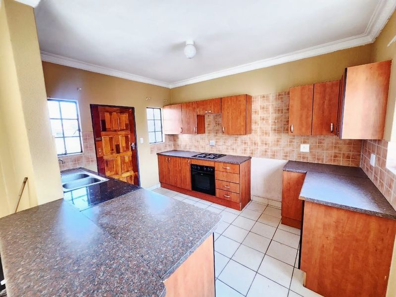 A functional kitchen featuring wooden cabinetry, laminate countertops, a built-in oven with gas hob, and tiled flooring, offering a practical layout for renovation.