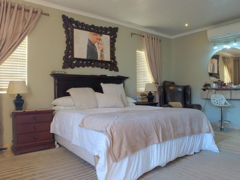 A well-maintained bedroom featuring tiled flooring, a tongue and groove ceiling, and a wall-mounted split-system air conditioner.