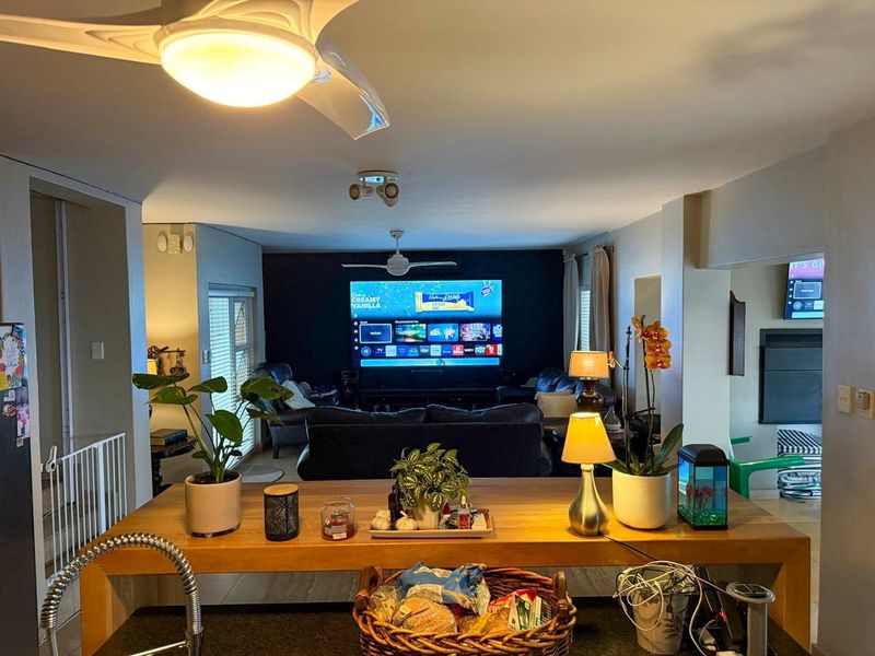 Open plan living area featuring a central kitchen island, ceiling fans, and integrated lighting, creating a functional and connected space.