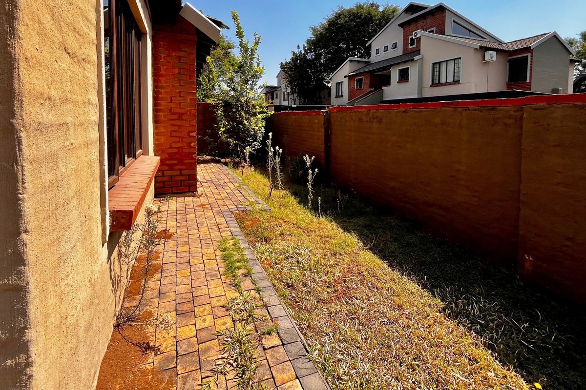 A side garden area featuring brick paving and a boundary wall, currently requiring landscaping and maintenance to improve the outdoor space's appeal.