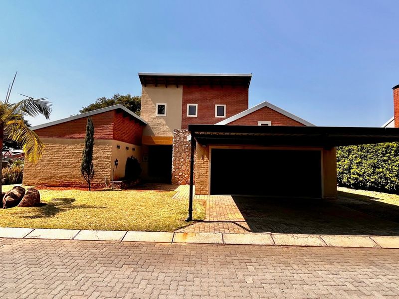 Front elevation of a multi-level house featuring a combination of brick and stone cladding, a paved driveway, and a covered carport.