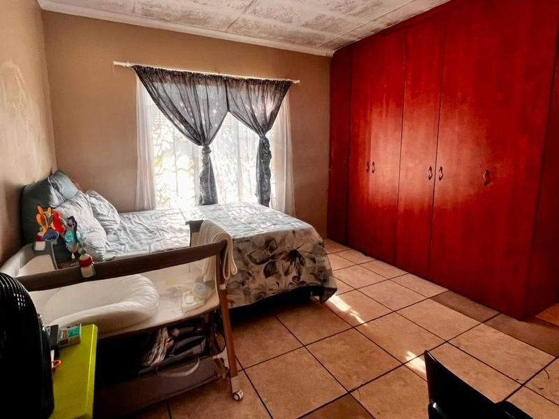 A bedroom featuring tiled flooring and floor-to-ceiling built-in cupboards, requiring cosmetic updates to the walls and ceiling to improve its overall condition.