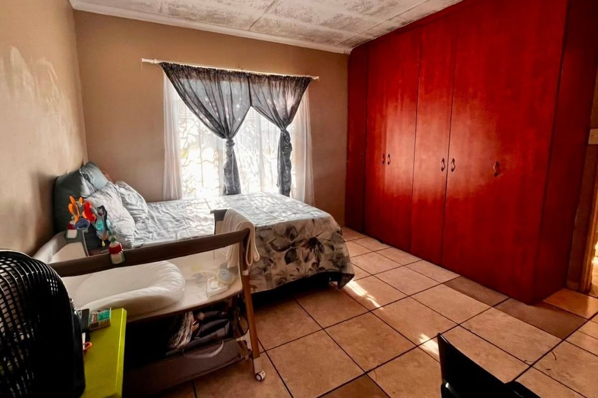 A bedroom featuring tiled flooring and floor-to-ceiling built-in cupboards, requiring cosmetic updates to the walls and ceiling to improve its overall condition.