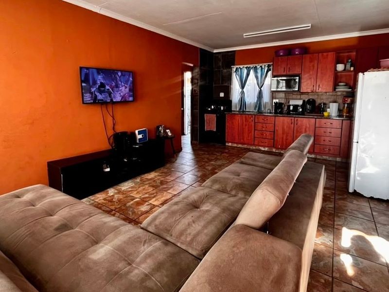 Open-plan living area featuring a kitchen with built-in cabinetry and tiled flooring throughout, creating a functional combined space.