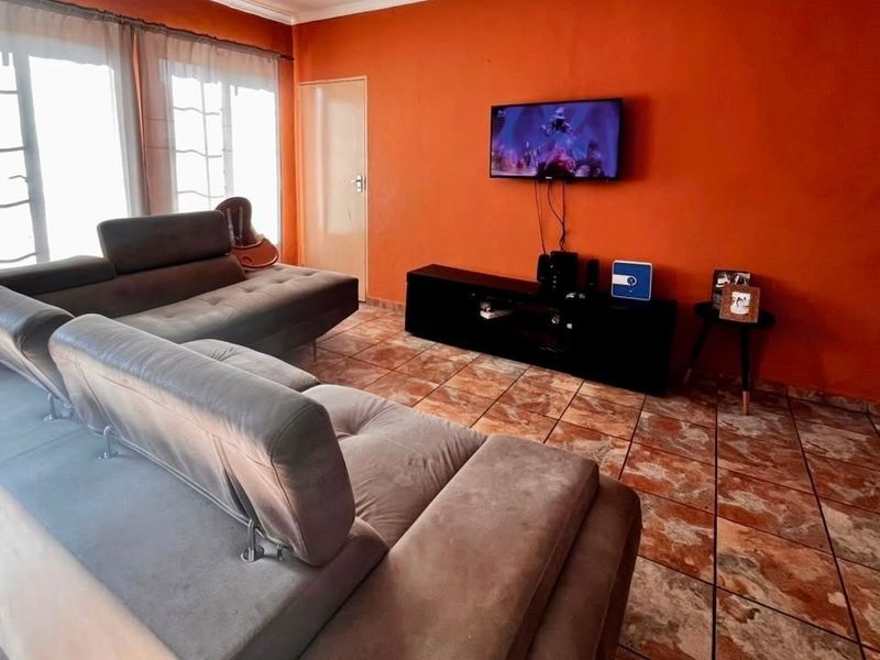 A living room featuring tiled flooring and large sliding glass doors that provide natural light.