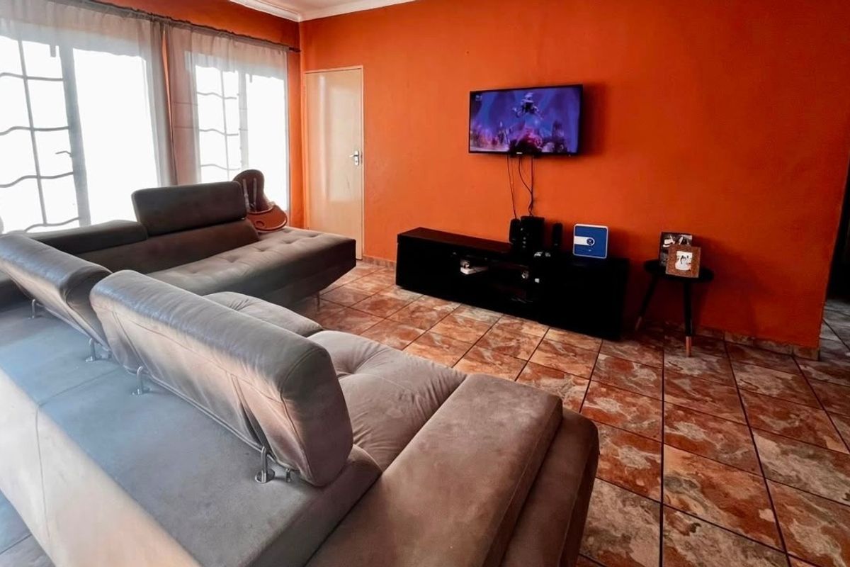 A living room featuring tiled flooring and large sliding glass doors that provide natural light.