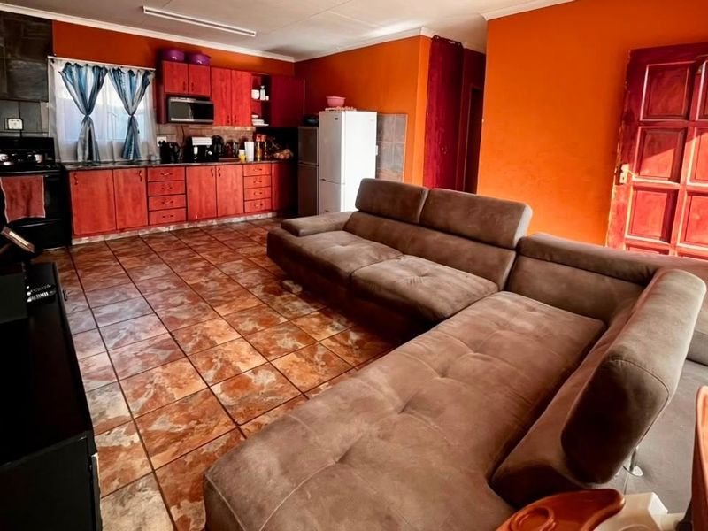 Open-plan living area featuring tiled flooring and a functional kitchen with built-in cabinetry, oven, and stove.