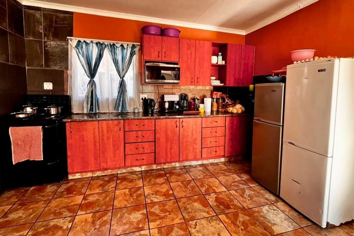 A functional kitchen featuring wooden cabinetry, granite countertops, and tiled flooring, offering a practical layout with built-in storage and preparation space.