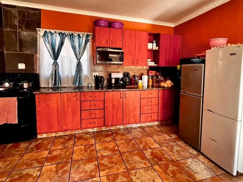 A functional kitchen featuring wooden cabinetry, granite countertops, and tiled flooring, offering a practical layout with built-in storage and preparation space.