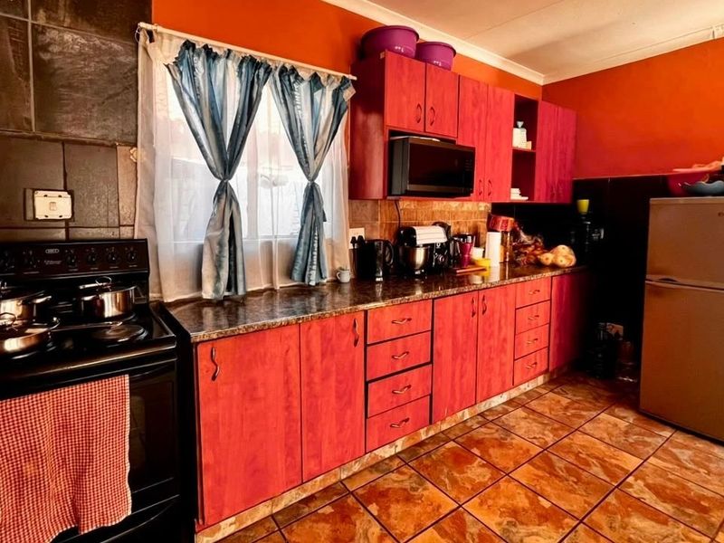 A functional kitchen featuring laminate cabinetry, granite countertops, tiled flooring, and a built-in stove, offering a practical layout for daily meal preparation.