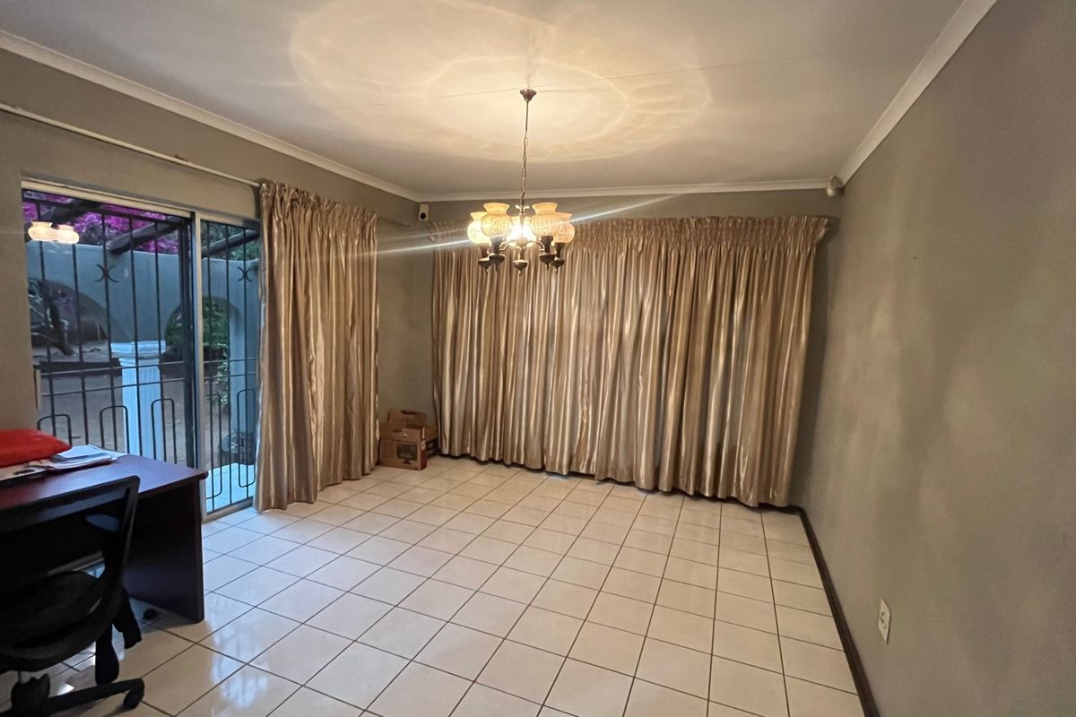 Spacious living area featuring ceramic tile flooring, a central chandelier, and sliding glass doors providing access to the outdoor area.