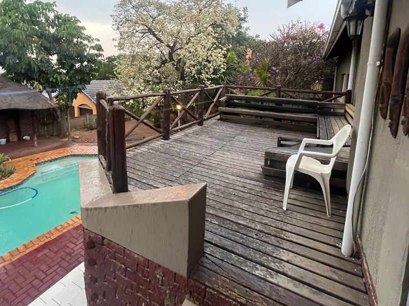 Elevated timber deck patio overlooking a swimming pool, featuring built-in bench seating and a timber balustrade.