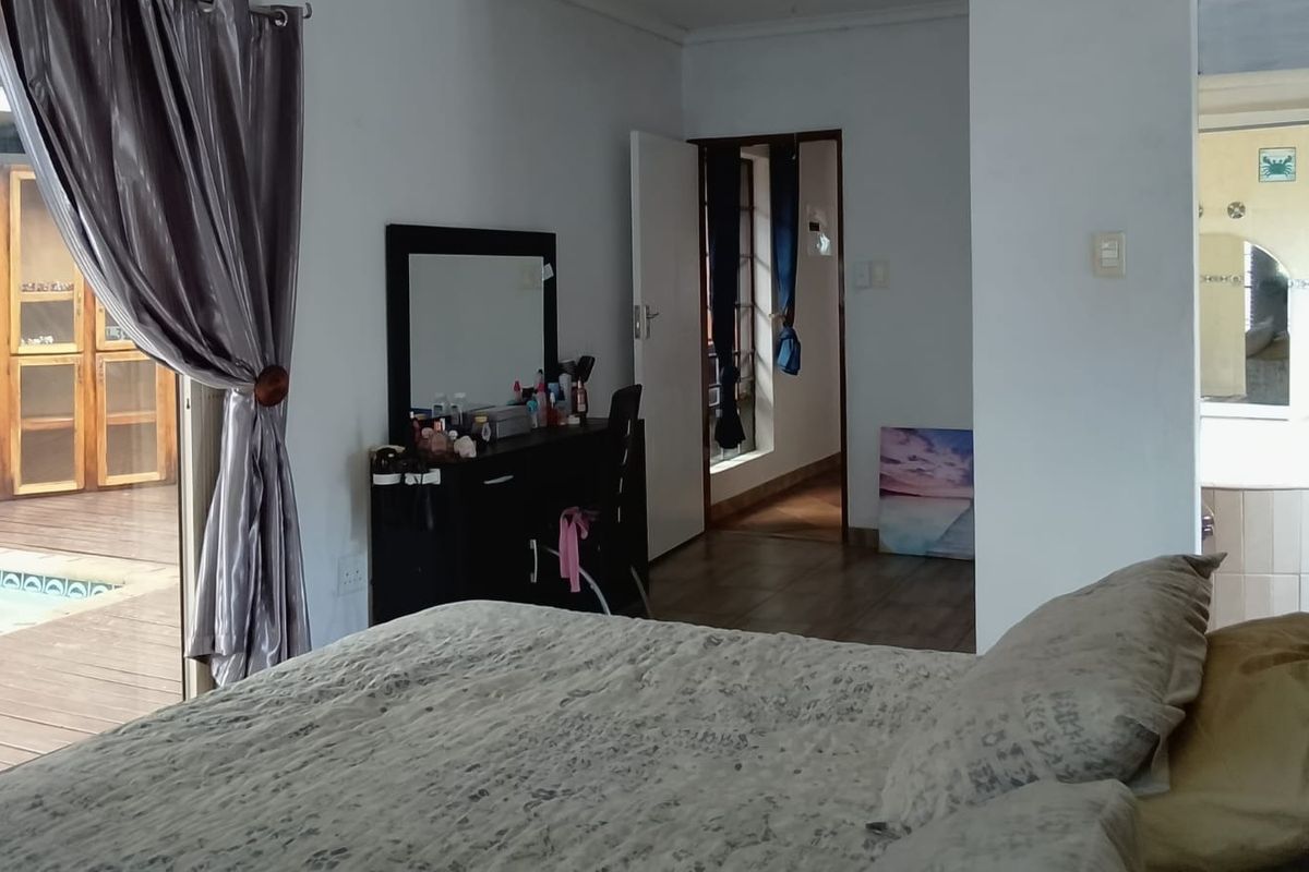 Spacious bedroom featuring tiled flooring, direct access to an outdoor patio area, and an adjoining en-suite bathroom.