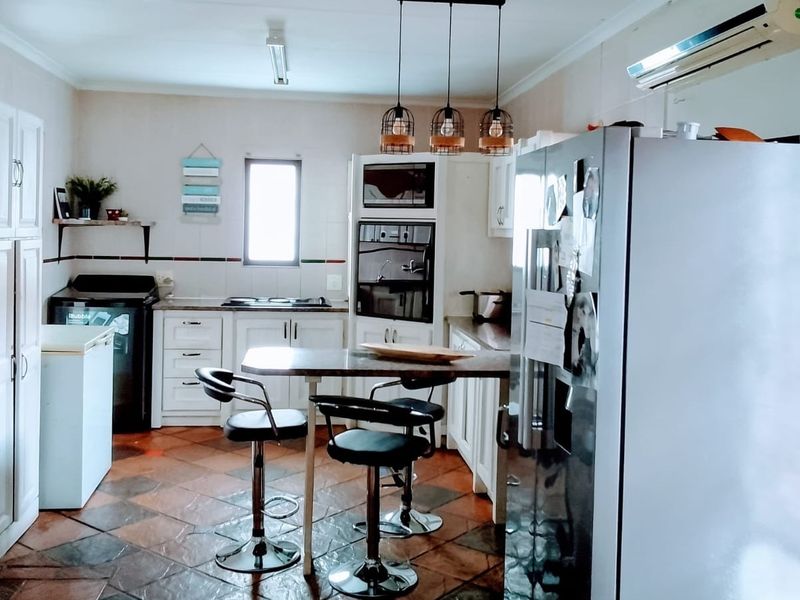 A functional kitchen featuring built-in cabinetry, integrated oven and microwave, tiled flooring, and a breakfast bar area with pendant lighting.