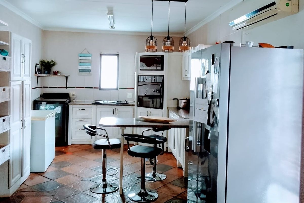 A functional kitchen featuring built-in cabinetry, integrated oven and microwave, tiled flooring, and a breakfast bar area with pendant lighting.