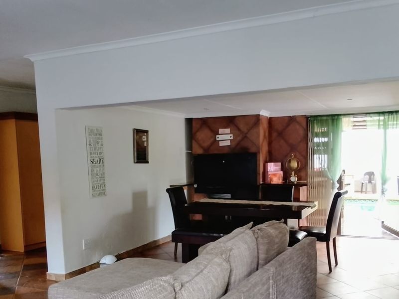 Open plan living area featuring tiled flooring, a built-in fireplace, and direct access to the outdoor patio area through a sliding door.