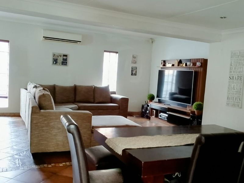 Spacious open-plan living and dining area featuring tiled flooring, recessed lighting, and a wall-mounted air conditioning unit.