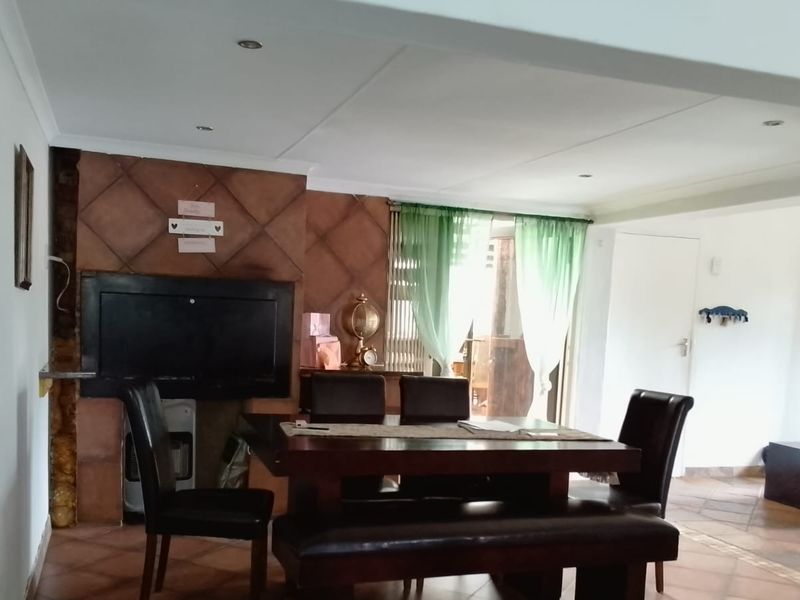 Dining area featuring a built-in fireplace with tiled surround, ceramic floor tiles, and recessed lighting, offering a functional space for family meals.