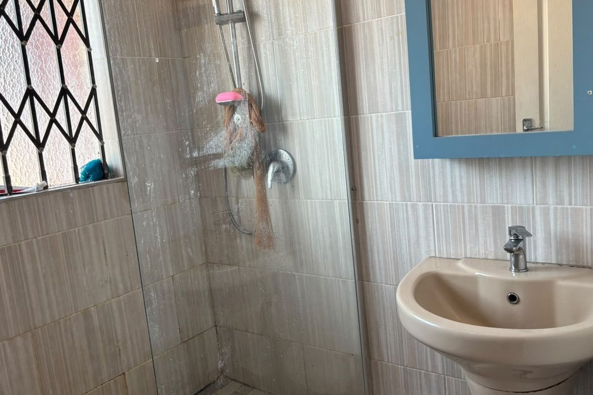 Bathroom featuring a pedestal basin, tiled walls, and a glass-enclosed shower area with a handheld shower fixture.