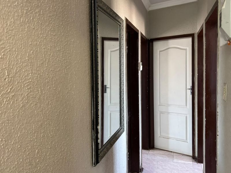 A functional hallway featuring textured walls, tiled flooring, and multiple doorways with dark wood frames, providing access to various rooms within the home.