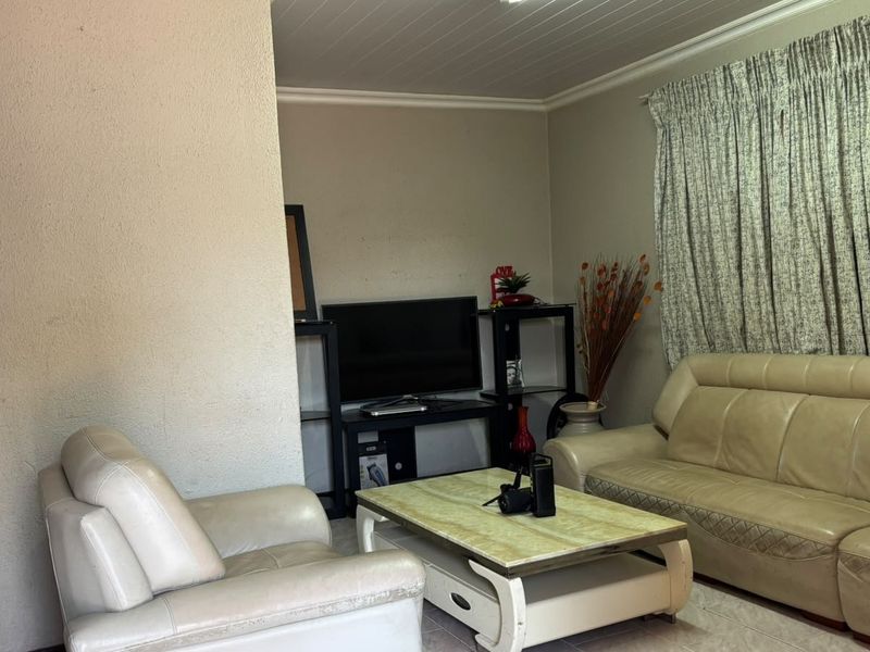 A living room featuring tiled flooring and coved ceiling details, providing a functional and neutral space for relaxation.
