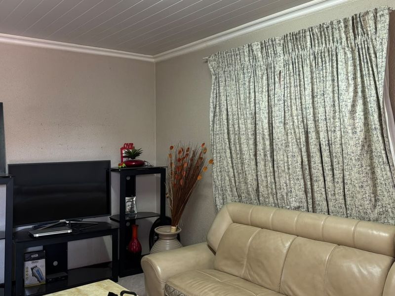 A living room featuring a tongue and groove ceiling with decorative cornice and window curtain tracks.