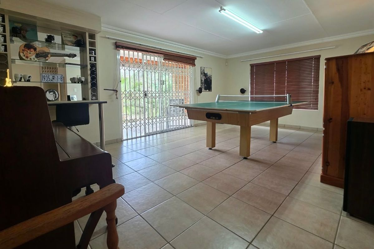 Spacious living area featuring tiled flooring, built-in shelving, and large sliding doors with security gates leading to the outdoor area.