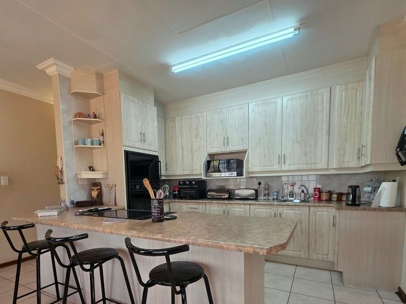 Functional kitchen featuring light wood-look cabinetry, a central island with breakfast bar seating, built-in oven, and tiled flooring.