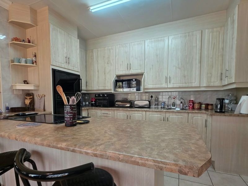 A functional kitchen featuring light-toned laminate cabinetry, ample countertop space, a breakfast bar, and integrated cooking appliances.