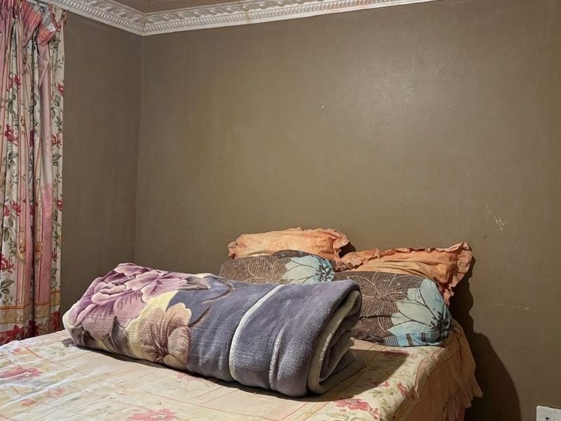 A bedroom featuring decorative ceiling cornicing and a window fitted with a security gate.