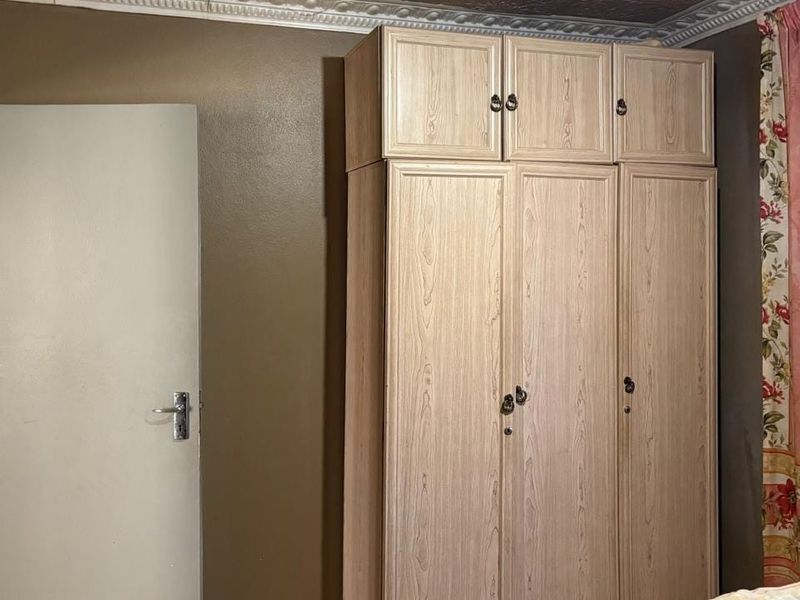 Bedroom featuring a built-in wooden wardrobe and decorative ceiling cornice, requiring cosmetic updates to the wall and ceiling finishes.