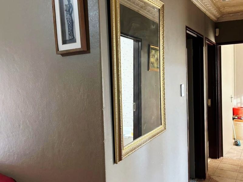 A hallway featuring tiled flooring and ornate ceiling cornicing, providing access to adjacent rooms within the property.