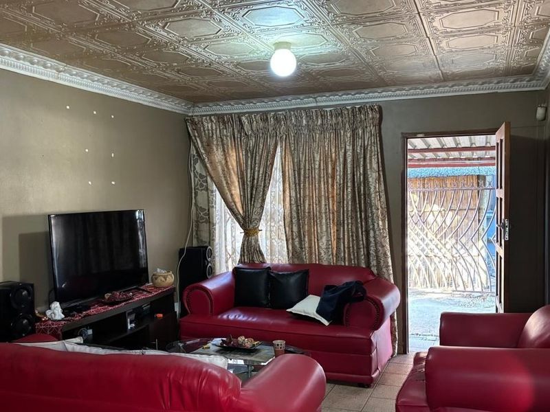 A living room featuring a decorative pressed metal ceiling, tiled flooring, and direct access to an outdoor area.