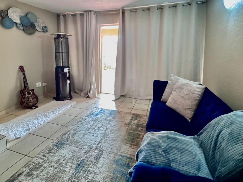 A living room featuring tiled flooring and a sliding glass door providing access to the exterior.