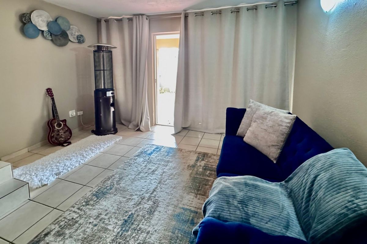 A living room featuring tiled flooring and a sliding glass door providing access to the exterior.