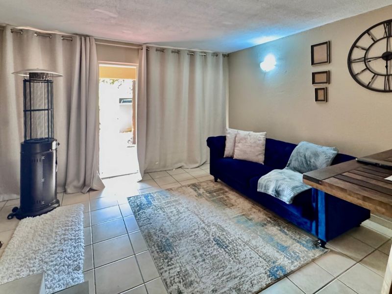 A living room area featuring tiled flooring and a sliding glass door providing access to the exterior.