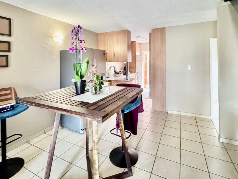 Open-plan living and kitchen area featuring tiled flooring, built-in cabinetry, and a staircase leading to the upper level.
