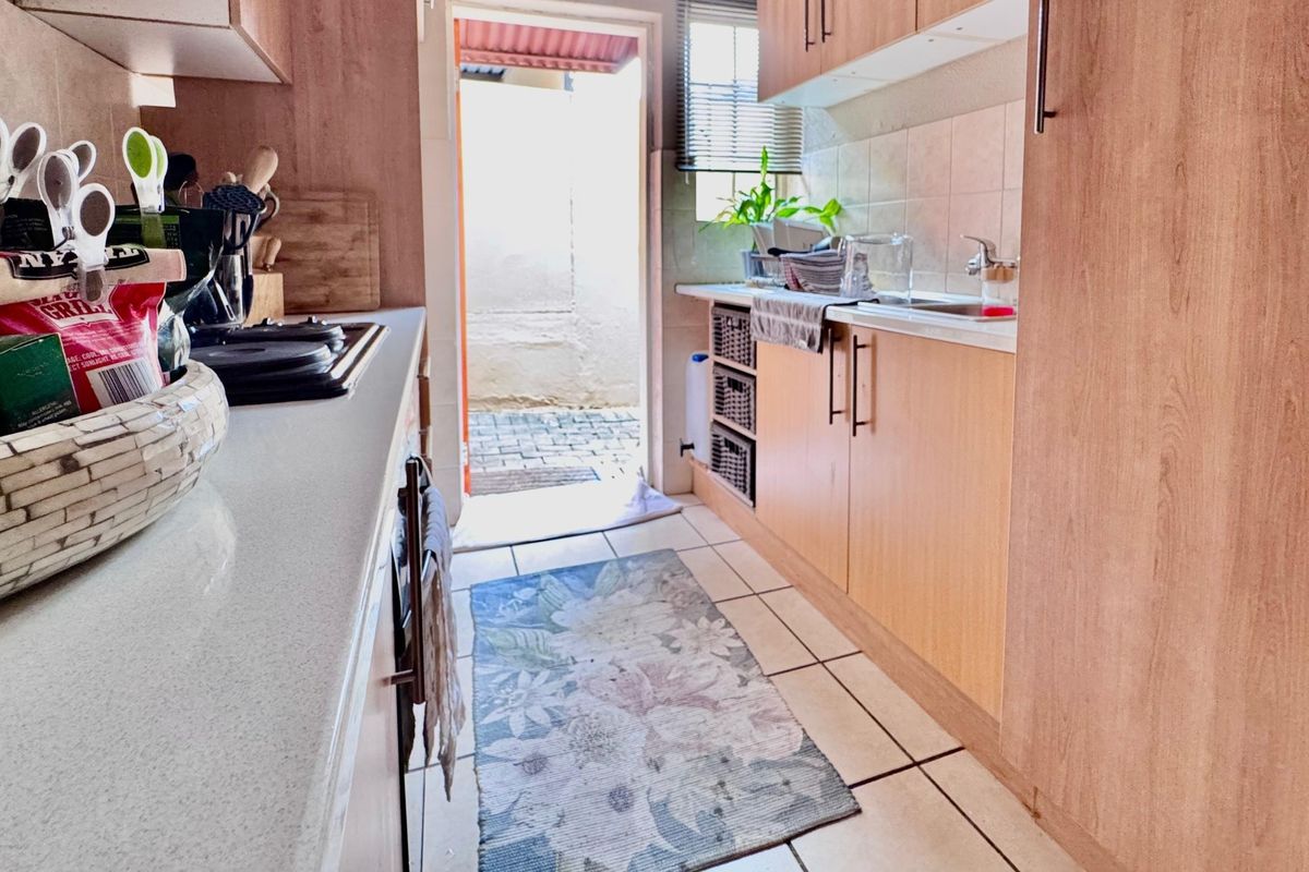 Functional galley-style kitchen featuring laminate cabinetry, stone countertops, and direct access to an outdoor area, providing a practical layout for daily meal preparation.