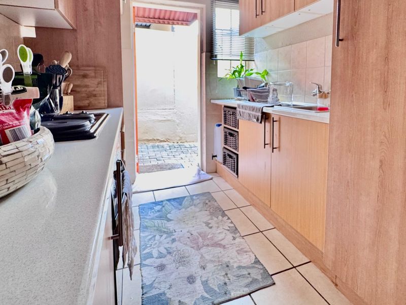 Functional galley-style kitchen featuring laminate cabinetry, stone countertops, and direct access to an outdoor area, providing a practical layout for daily meal preparation.
