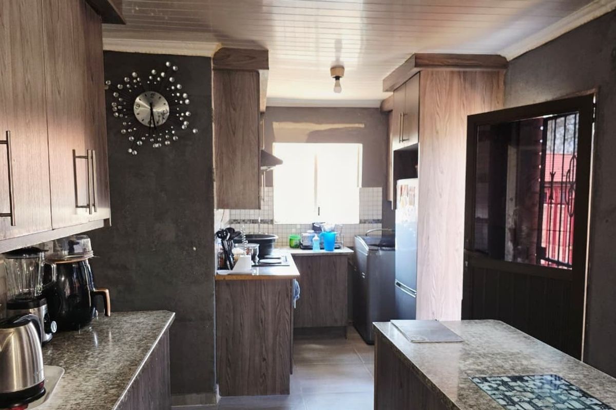 A kitchen featuring wood-look cabinetry and countertops, with unfinished wall surfaces and tiled flooring, offering potential for cosmetic renovation.