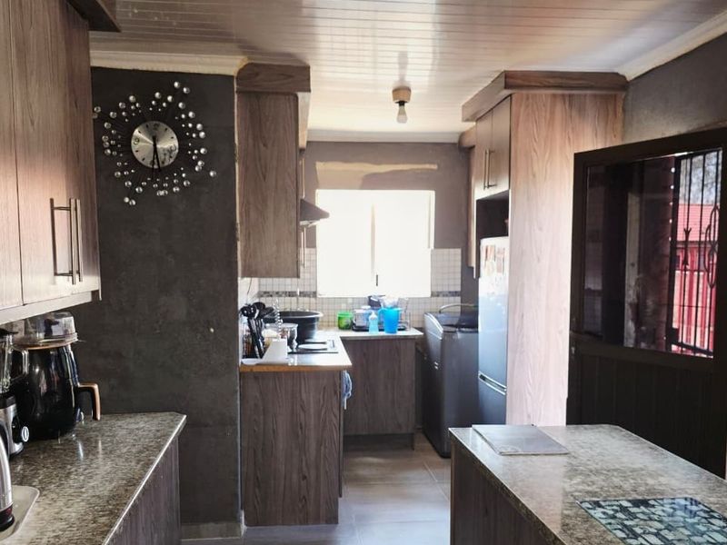 A kitchen featuring wood-look cabinetry and countertops, with unfinished wall surfaces and tiled flooring, offering potential for cosmetic renovation.