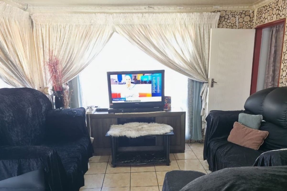 A living room featuring tiled flooring and decorative ceiling cornicing, offering a functional space that could benefit from modern updates.