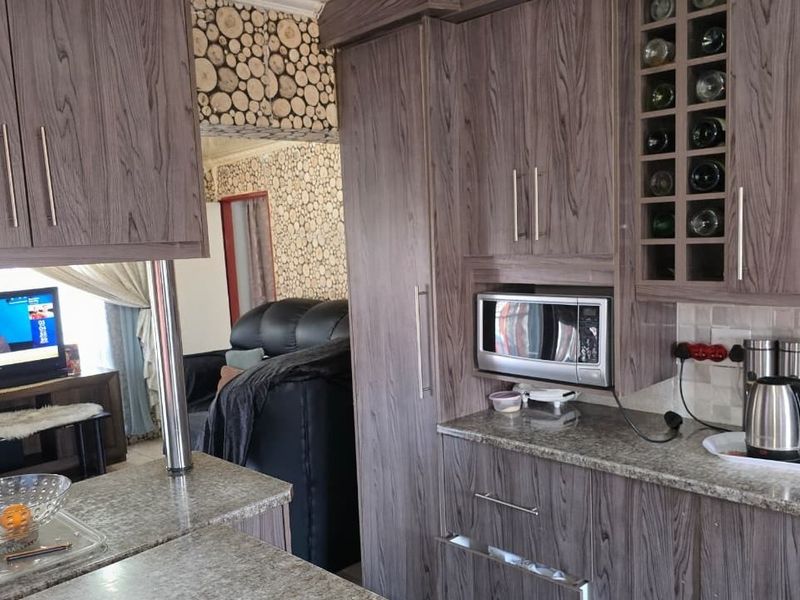 Open plan kitchen featuring wood-grain cabinetry, granite countertops, and a built-in microwave, seamlessly connecting to the adjacent living area.