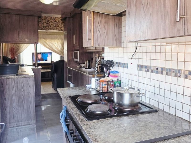 Functional kitchen featuring laminate cabinetry, granite-look countertops, and a built-in electric hob with extractor fan, offering a practical layout for daily cooking.