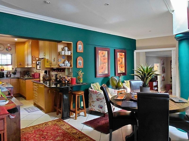 Open-plan living and dining area featuring a connected kitchen with built-in cabinetry, granite countertops, and tiled flooring throughout.