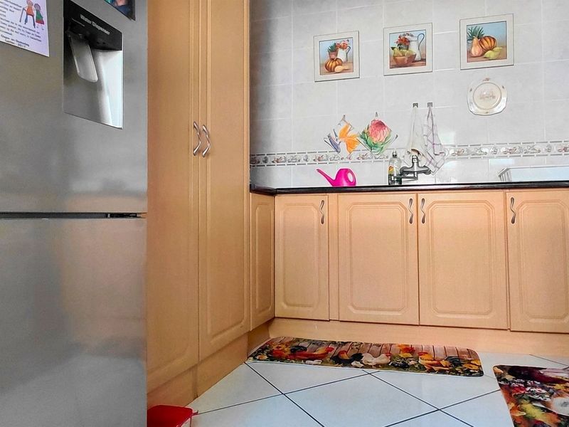 A functional kitchen featuring light-toned built-in cabinetry, tiled backsplash, and tiled flooring, providing a practical workspace with integrated storage solutions.