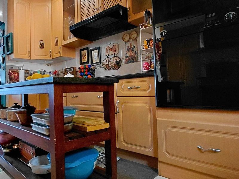 A functional kitchen featuring traditional timber cabinetry, a built-in oven, extractor fan, and stone countertops with a tiled backsplash.
