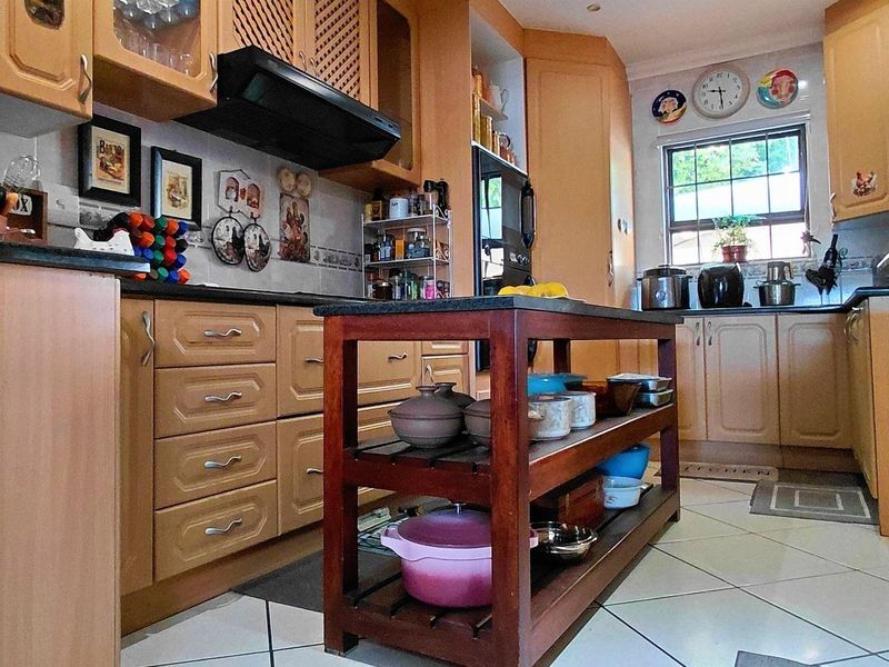 A functional kitchen featuring wooden cabinetry, granite countertops, tiled flooring, and an integrated extractor fan, offering a classic layout with ample storage space.